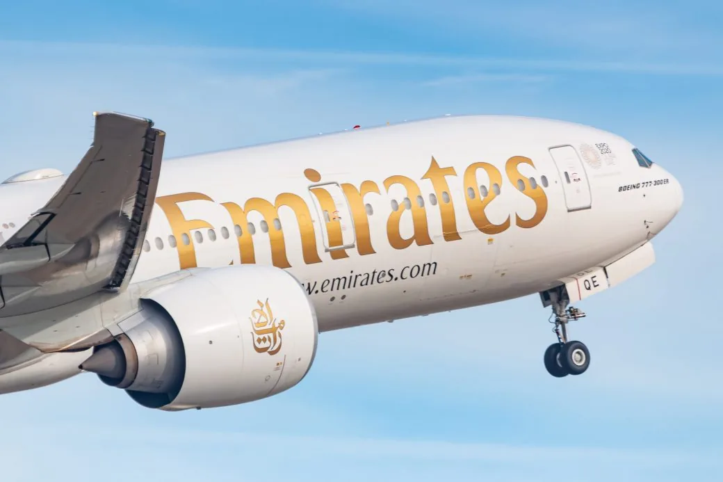 Close-up of an Emirates aircraft climbing against a clear sky.