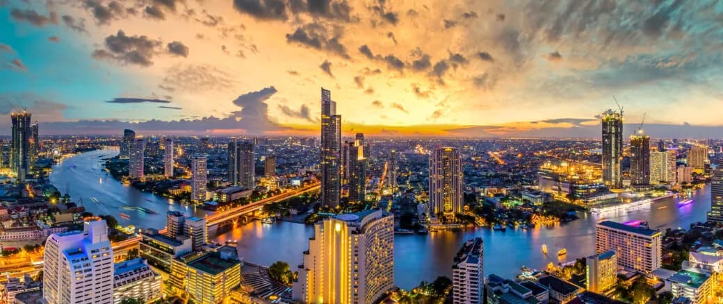 A river winding through a city skyline lit up at dusk.