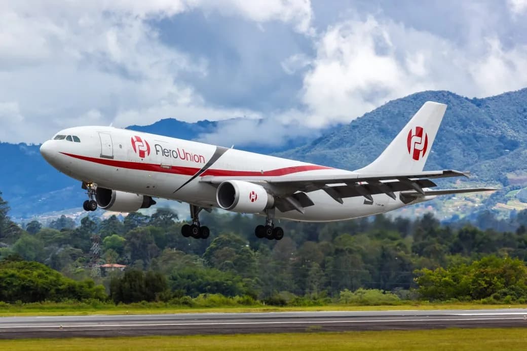 An AeroUnion cargo aircraft taking off with forested mountains in the background.