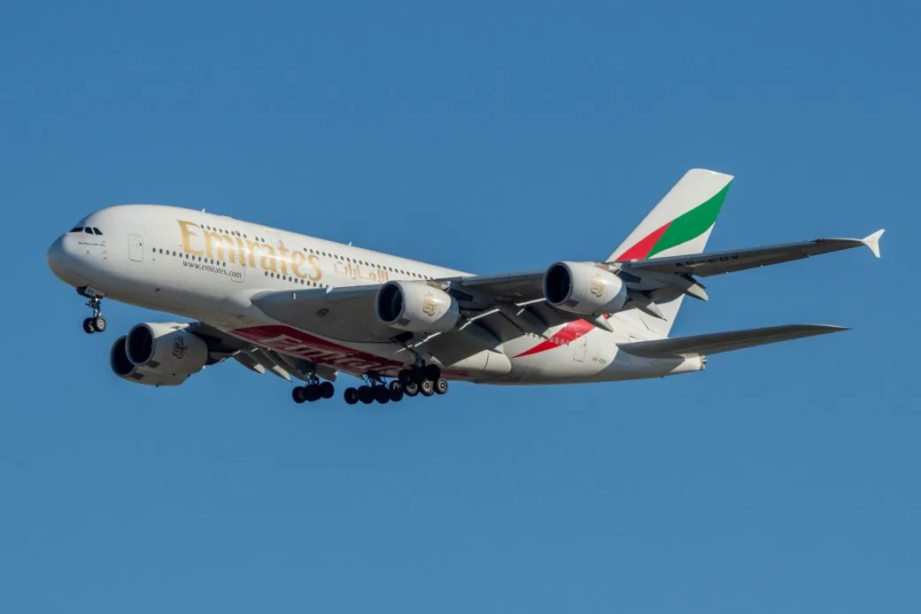 An Emirates Airbus A380 in flight against a clear blue sky.