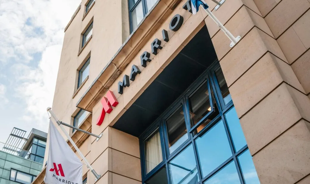 A Marriott hotel sign and logo mounted above the entrance of a stone building.