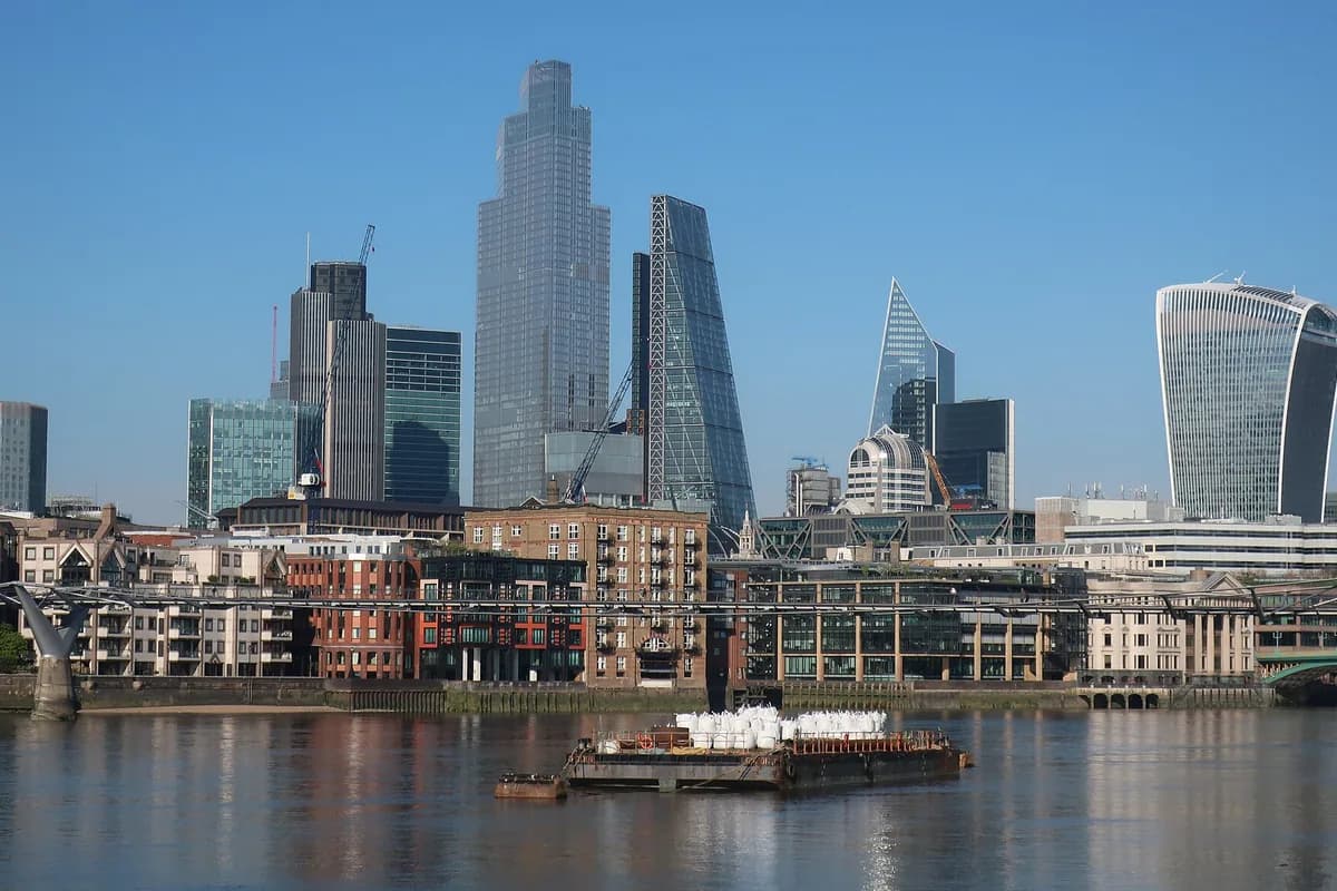 The City of London skyline across the Thames, with the towers of the Square Mile against a clear sky.