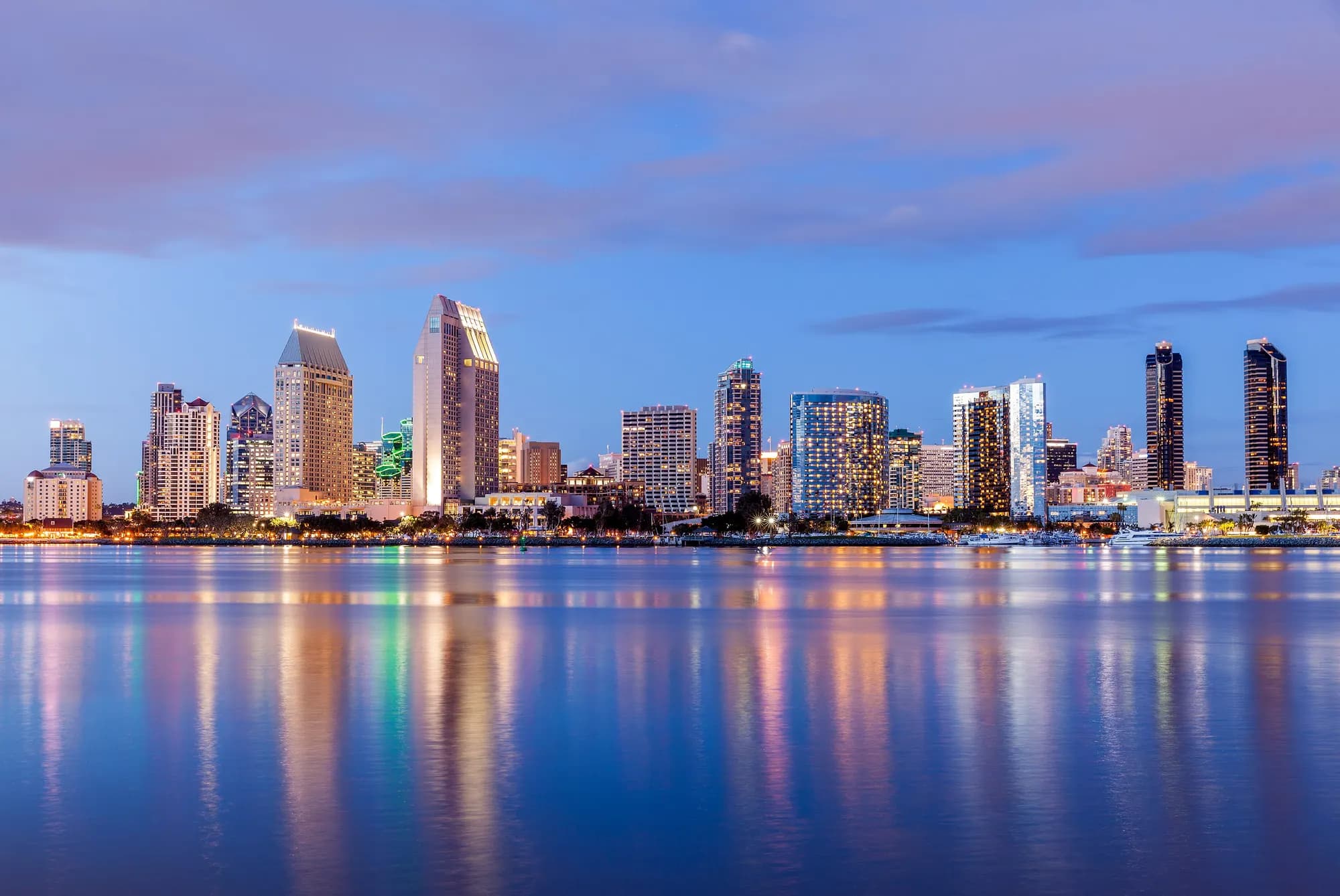 The San Diego downtown skyline at dusk, reflected across the bay from Coronado.